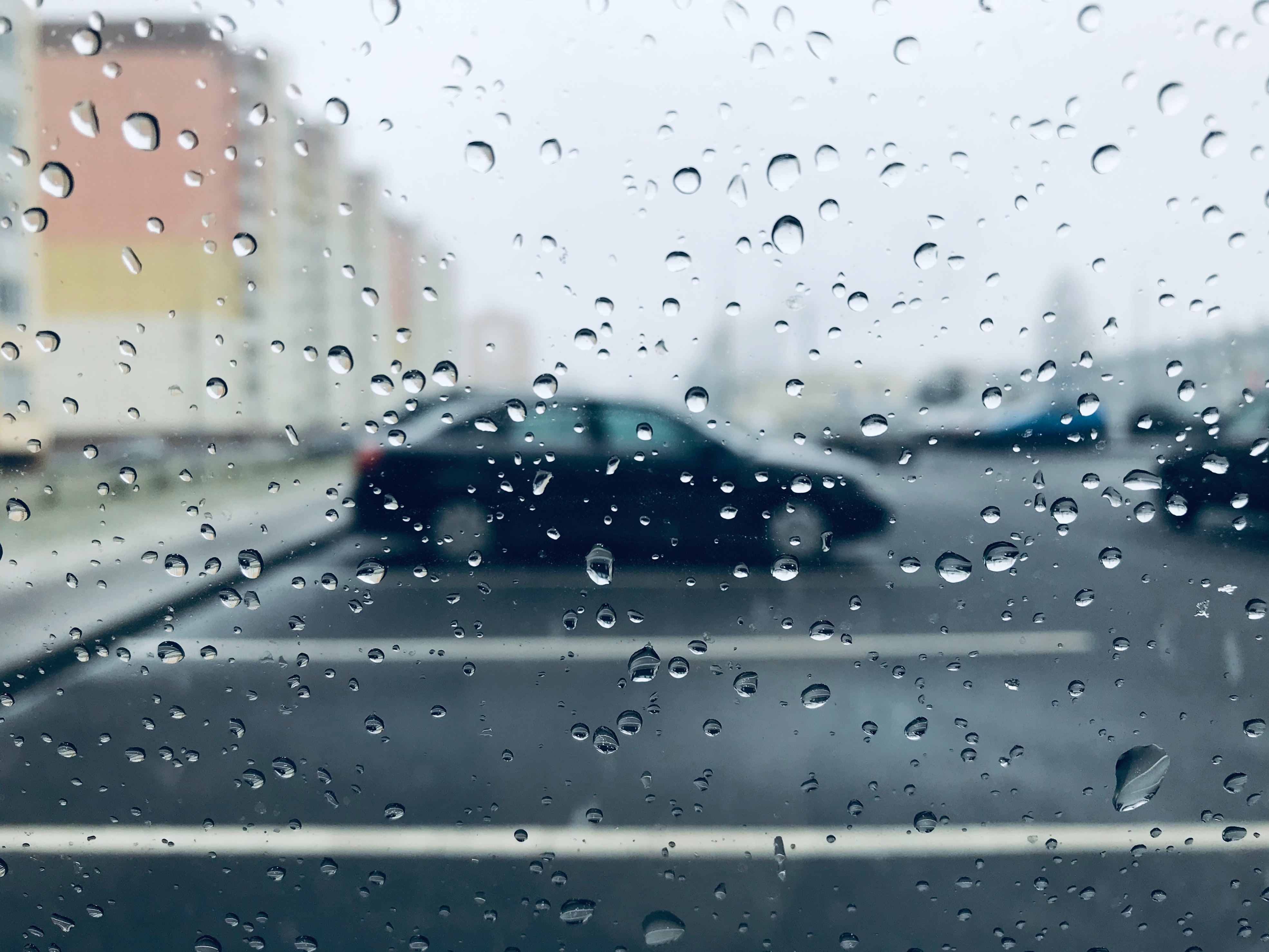 view of unfocused parked car through water droplets